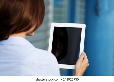 Over The Shoulder View Of A Woman Holding A Tablet Computer So That The Blank Black Screen With Copyspace Is Visible To The Viewer