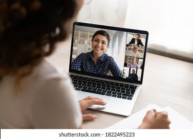 Over Shoulder View Of Woman Look At Laptop Screen Have Webcam Team Meeting Or Briefing With Colleagues. Female Employee Talk On Video Call On Computer, Engaged In Digital Virtual Event With Coworkers.