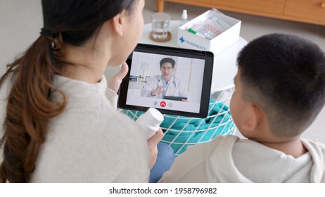 Over shoulder view of young asia parents and son talk to doctor on cellphone videocall conference medical app in telehealth telemedicine online service hospital quarantine social distance at home.