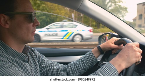 Over speed man with glasses is driving a car, his hand is on the steering wheel. Moving along the route  city. Road traffic. The police background.