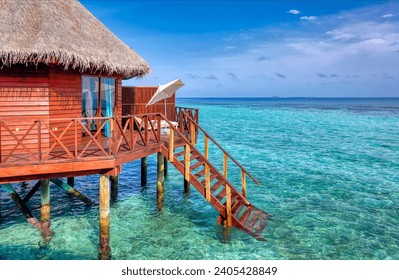 Over water bungalow on stilts with stairs into blue ocean on a tropical island, Maldives, Indian ocean