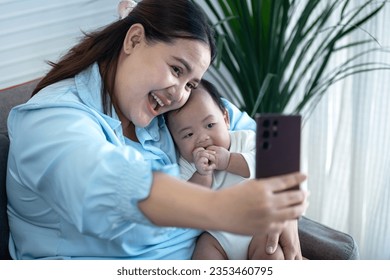 Over weight Asian mother taking selfie with her newborn baby boy on smartphone at home, Mothers' Day, Maternity concept - Powered by Shutterstock