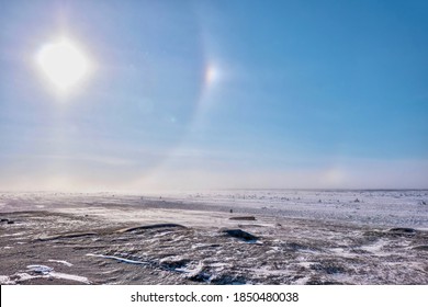 Over the winter tundra in Churchill, Canada, the atmospheric phenomenon known as a sun dog, or parhelion, is caused by the refraction of sunlight through ice crystals high in the atmosphere.