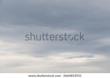 Overcast sky with thick gray clouds stretching across the horizon, creating a calm yet moody atmosphere above a distant landscape.