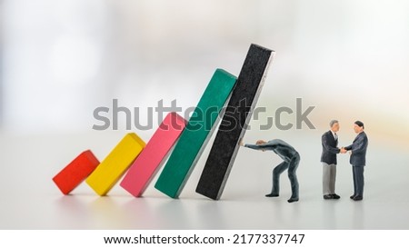 Overcoming fear of failure, domino effect or chain reaction, psychology concept : Businessman CEO as an action taker pushes and prevents wood bar graph from collapsing, two dearlers negotiate a deal.