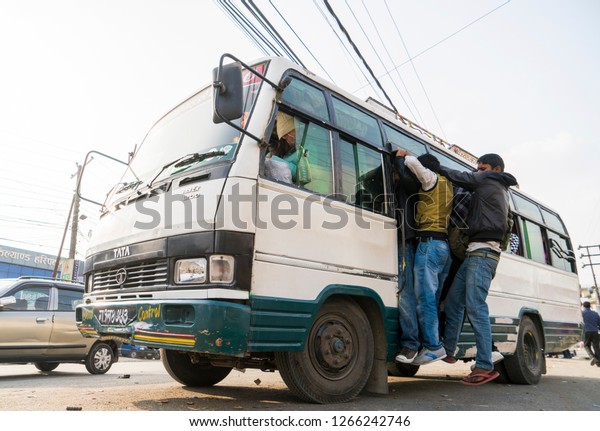 Overcrowded bus with people\
gripping its doors. Fuel crisis in Nepal. Captured in Nepal in\
winter 2015