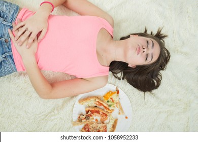 Overeat Girl With Closed Eyes Lying On Bed With Pizza