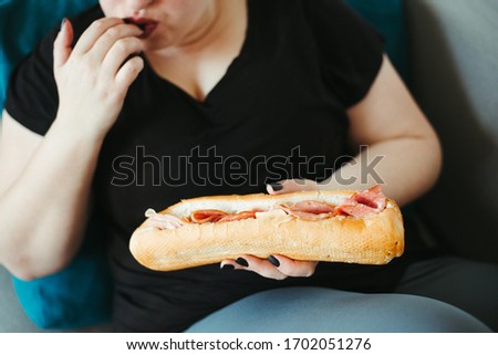 Overeating and gluttony concept. Mindless snacking, home sedentary lifestyle. Obese woman eating huge portion of unhealthy food