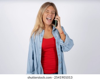 Overemotive happy Beautiful teen girl wearing denim jacket laughs out positively hears funny story from friend during telephone conversation - Powered by Shutterstock