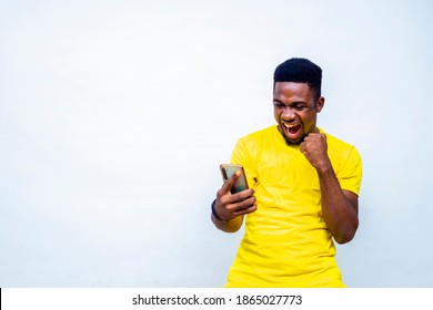 Overexcited Young Black African Male Hipster Celebrating After Receiving Good News Form Mobile Phone Chatting With Friends Online