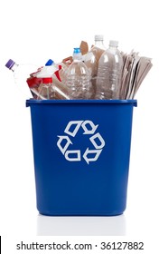 An Overflowing Blue Recycle Bin Full Of  Plastic Bottles, Newspapers And Boxes, With The Recyle Symbol On Front