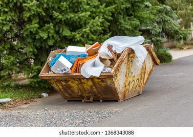 Overflowing Rusty Metal Container For Construction Waste With Cardboard Boxes And Other Plastic Trash