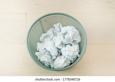 Overflowing waste paper in office garbage bin. Junk, wastepaper in rubbish isolated on wooden background. Trash concept