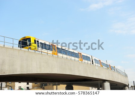 Overground Train moving slowly on the upper track with blue sky background in Shoreditch, London, England