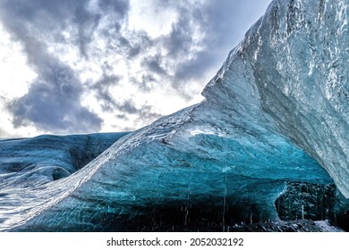 The overhang of a glacial ice cave in Iceland. The caves are coloured in shades of blue, and often have layers of black, formed from volcanic ash.