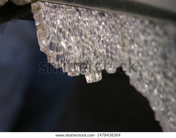 An overhanging heavy crystal hung in the darkness,\
ready to fall down and pierce. Indifferent to the victim weapon of\
fate (allegorically). close-up of broken tempered old car glass.\
shallow focus.