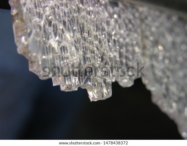 An overhanging heavy crystal hung in the darkness,\
ready to fall down and pierce. Indifferent to the victim weapon of\
fate (allegorically). close-up of broken tempered old car glass.\
shallow focus.