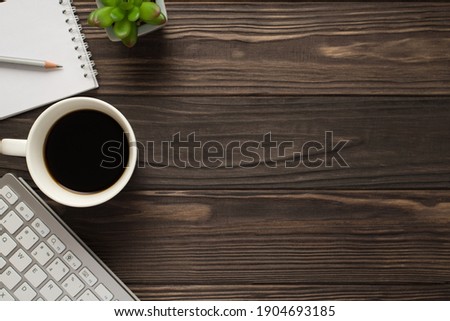 Overhead above view photo of coffee copybook succulent green plant keyboard on dark textured backdrop