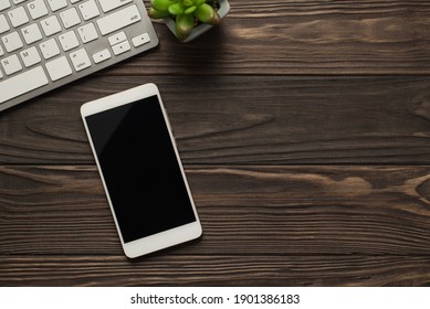 Overhead above view photo of keyboard succulent and mobile phone with copyspace on screen on dark wooden backdrop - Powered by Shutterstock