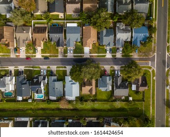 Overhead Aerial Drone Picture Of Middle Class House In Rows In Middle Class Suburban Neighborhood. Grey And Neutral Colored Homes With Cars And Intersecting Street In Florida.