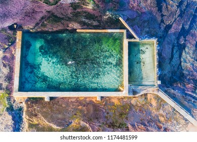 Overhead Aerial View Down To Mona Vale Rock Pool With Swimming Man In Sea Water From Pacific Ocean Tide Over Sandstone Rock Plateau.