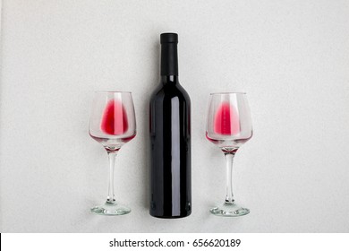 Overhead Angled View Of A Large Bottle Of Red Wine, Drinking Glasses On White Background