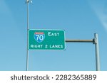 overhead brightly colored steel highway sign for interstate 70 east right two lanes of high way exit ahead