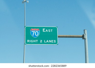 overhead brightly colored steel highway sign for interstate 70 east right two lanes of high way exit ahead