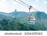 Overhead cable car riding through the mountain with Tian Tan Buddha statue on the far peak. It is one of transportations to the tourist attractions located at Ngong Ping in Lantau Island, Hong Kong.