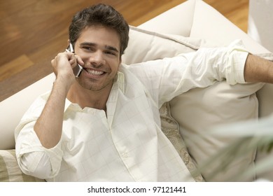 Overhead close up of a professional man using a cell phone while laying down on a sofa.