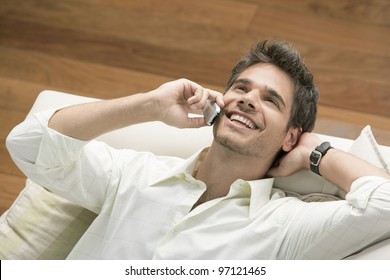 Overhead Close Up Of A Professional Man Using A Cell Phone While Laying Down On A Sofa.