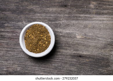 Overhead Close Up View Of A Bowl Of Ground Red Cayenne Pepper On A Weathered Heavily Textured Wooden Background With Copyspace