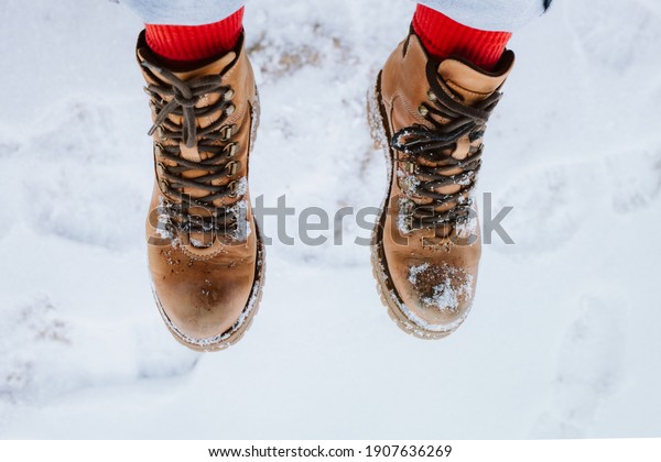 Overhead closeup\
shot of female legs in winter boots playfully stepping on snow. Top\
view of female hiker\
shoes.