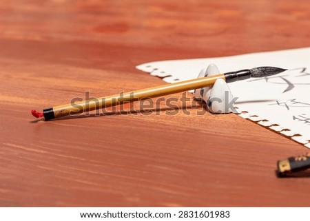 Overhead composition of Mandarin language study session with wooden desk, traditional calligraphy equipment, and practice sheet containing basic introductory Chinese words.