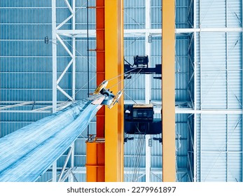 Overhead crane inside factory building, industrial background.