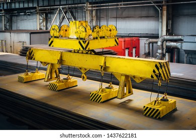 Overhead crane with magnetic grippers lifting steel sheets.