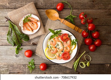 Overhead Of Dinner Table. Seafood Casserole With Leek, Cheese, Grilled Shrimps, Serving With Tomato Cherry, Parsley And Basil. Healthy Diet Seafood Concept. Top View.Rustic Style. 