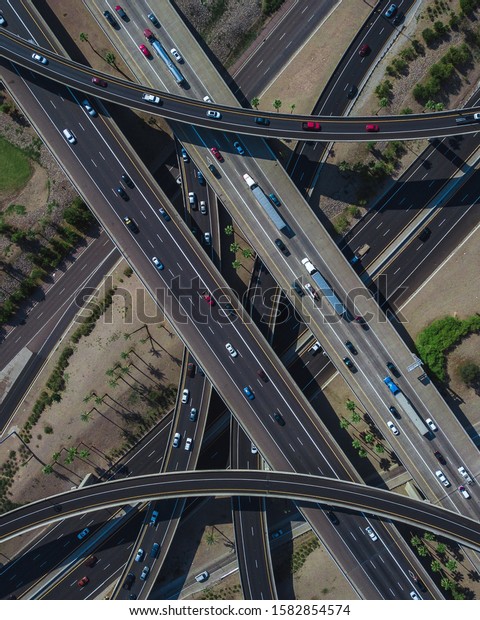 An overhead drone shot of a busy highway\
intersection full of traffic during\
daytime