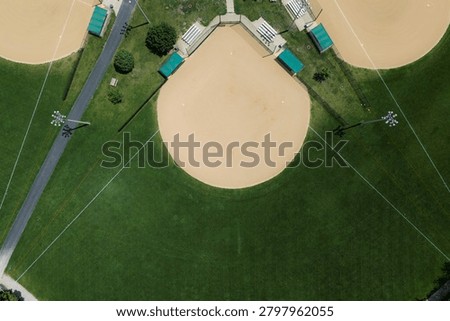 An overhead drone view captures a well-maintained clay baseball infield surrounded by green outfield grass, bleachers, and recreational facilities in Elgin, Illinois.