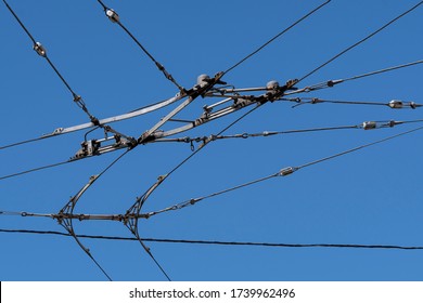 Overhead electric bus wires backed by clear blue sky.