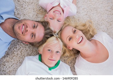 Overhead Of Family Lying On The Carpet At Home