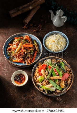 An overhead flat lay of an Asian dinner table featuring crispy shredded beef, vegetable stir-fried noodles, egg fried rice, chili oil, and a ceramic teapot.