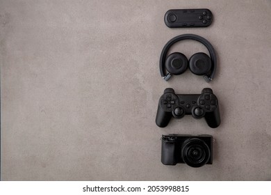 Overhead flat lay of black technology devices and gadgets on a grey background - Shutterstock ID 2053998815