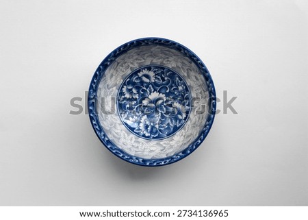 Overhead flat lay of blue and white decorative ceramic bowl with classic floral pattern, isolated on white background, photographed using soft diffused lighting and clean composition.
