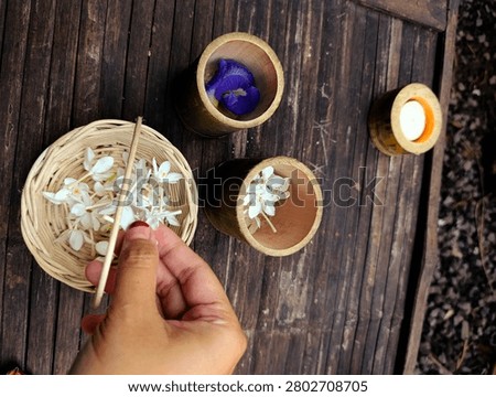 Overhead Flatlay Hand Arranging White Jasmine and Blue Butterfly Pea in Wicker Basket Bamboo Candle