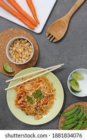 Overhead Flatlay Pad Thai Dish With Carrots Peanuts Peas And Limes On Gray Background