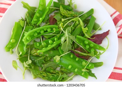 Overhead Of Fresh Snap Peas And Asparagus On White Plate With Dish Towel