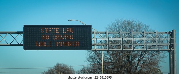 An overhead highway sign reminds drivers that driving under the influence is illegal.