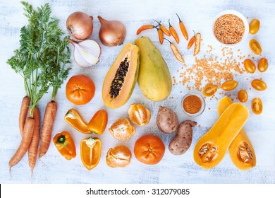 Overhead Horizontal Of Fresh Orange Toned Vegetables And Fruit Raw Produce On White Rustic Background, Pumpkin Butternut Carrot Papaya Pawpaw Capsicum Pepper Sweet Potato Cherry Tomatoes Chilli Orange