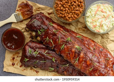 Overhead Image Of An All American Meal Of BBQ Smoked Pork Ribs With Baked Beans, Cole Slaw And Sauce 